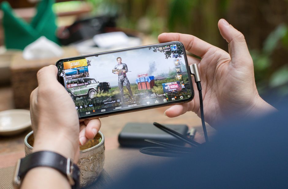 屋外でスマートフォンのゲームをプレイしている人の手元。モバイル中心の報酬型動画広告が届く場面のイメージ画像